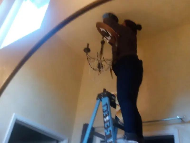 Electrician installing a chandelier in a Fabius residence